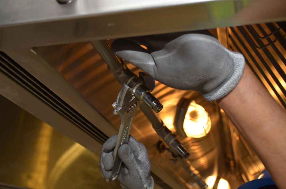 Gloved hand working under a fixture with a work light