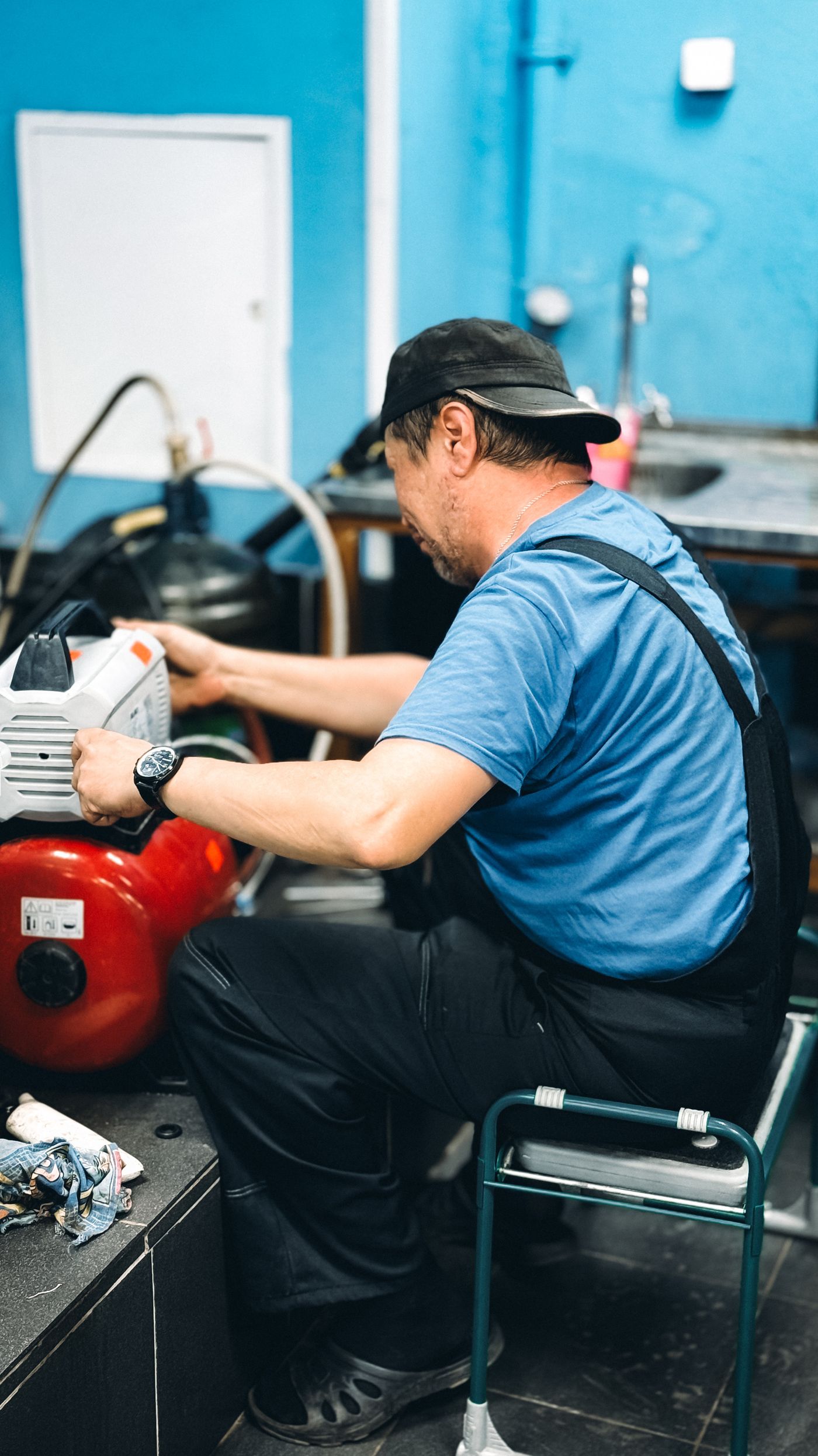 Plumber kneeling beside a water heater while working on a valve